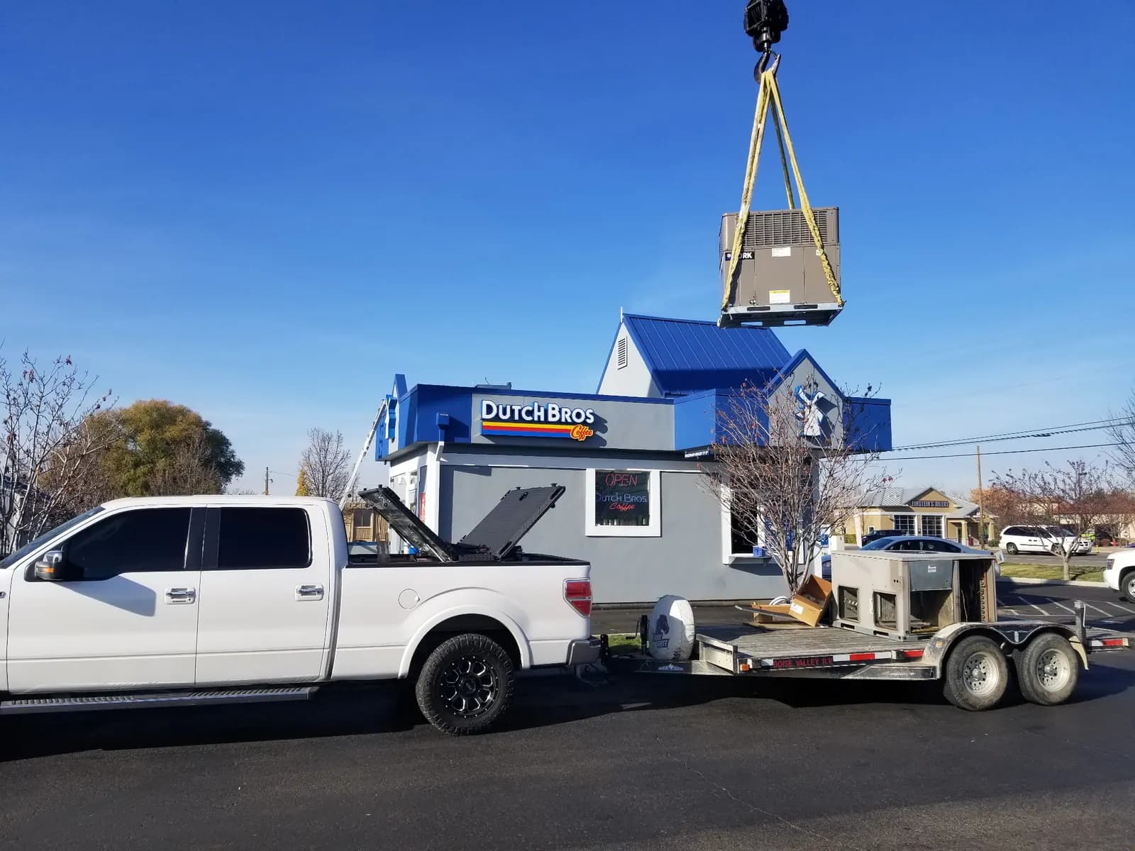 Commercial HVAC equipment delivery with crane and service truck