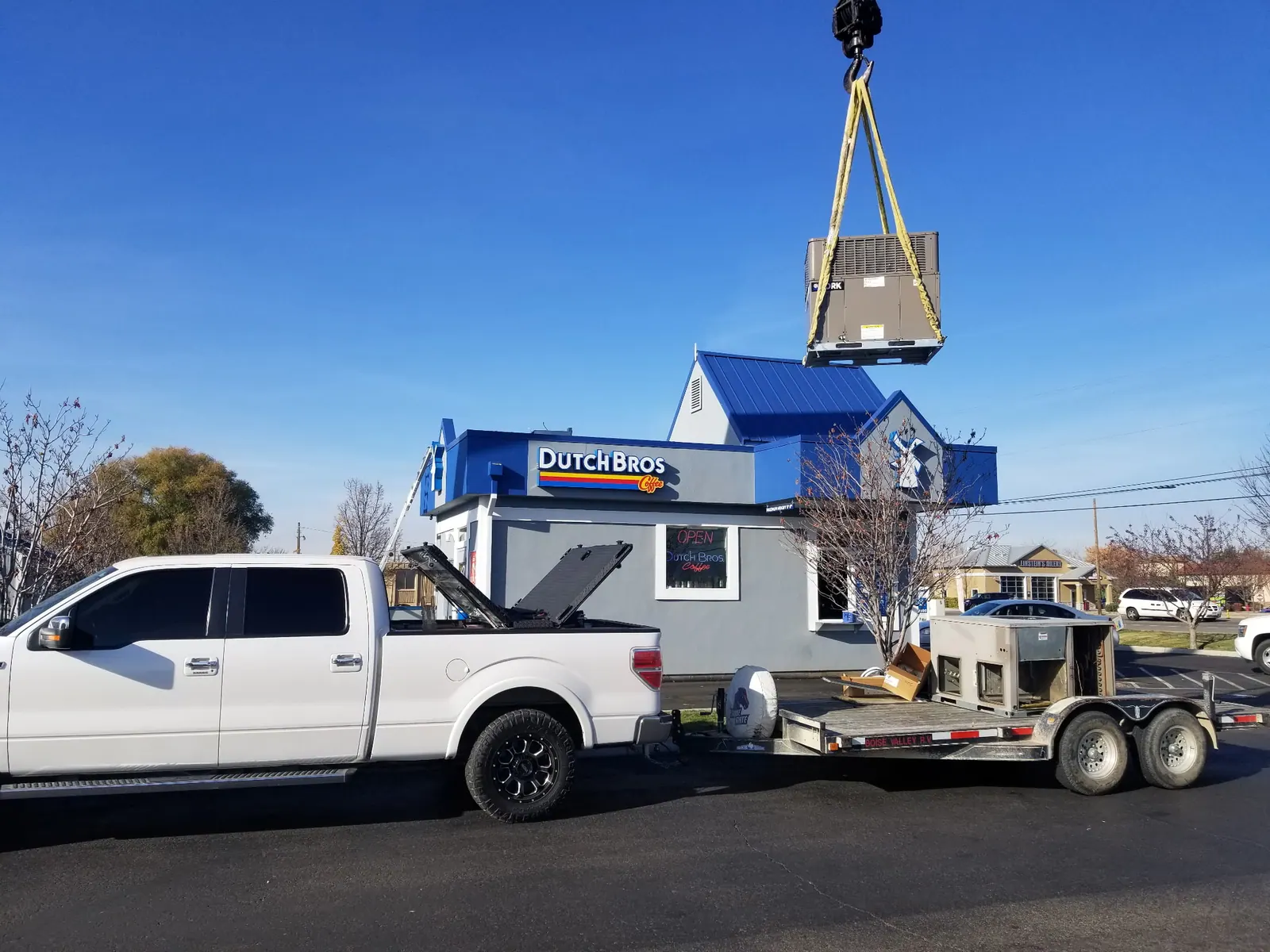 Commercial HVAC equipment delivery with crane and service truck
