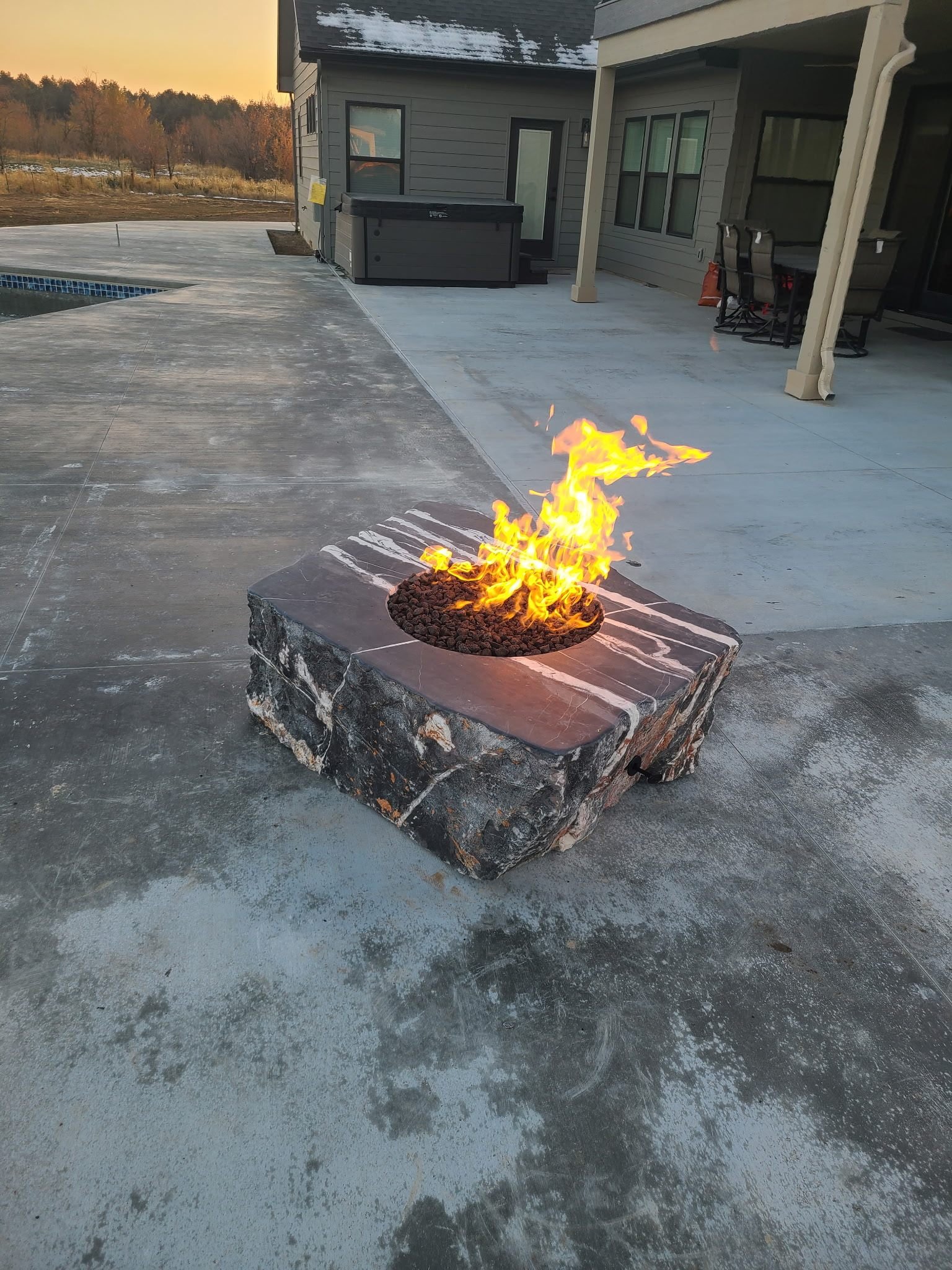 Outdoor gas fire pit burning on a concrete patio