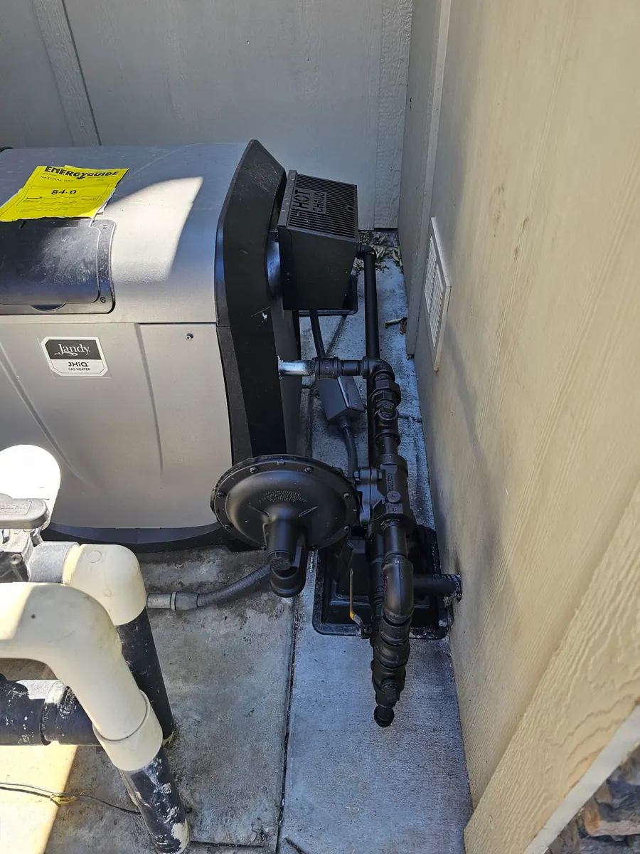 Black iron gas piping routed beside pool heater equipment
